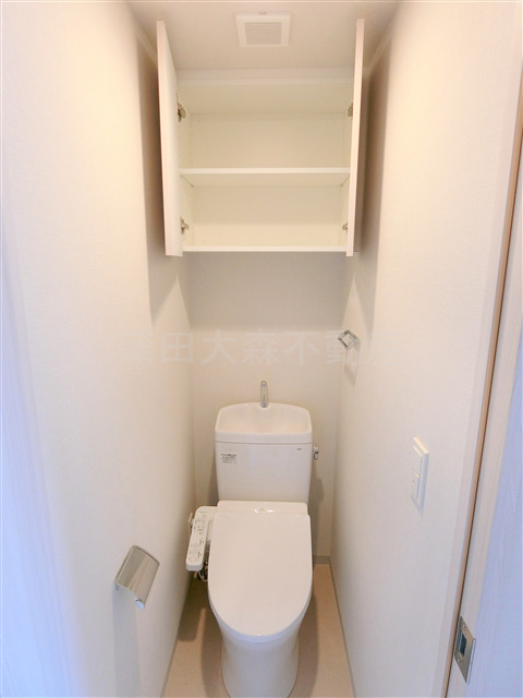 トイレ　吊戸棚と温水洗浄便座付きのトイレ