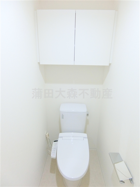 トイレ　吊戸棚と温水洗浄便座付きのトイレ