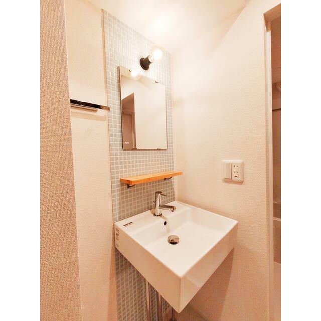 洗面設備　爽やかなタイルとミニマルな洗面台が映える清潔感ある空間。小棚