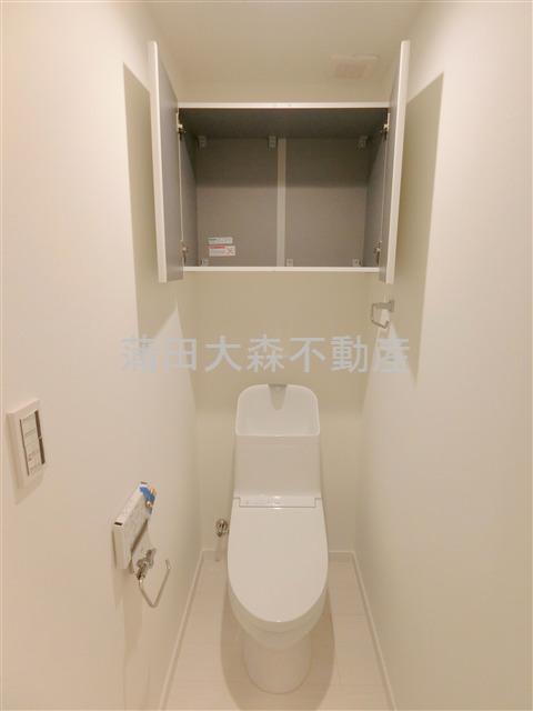 トイレ　吊戸棚と温水洗浄便座付きのトイレ