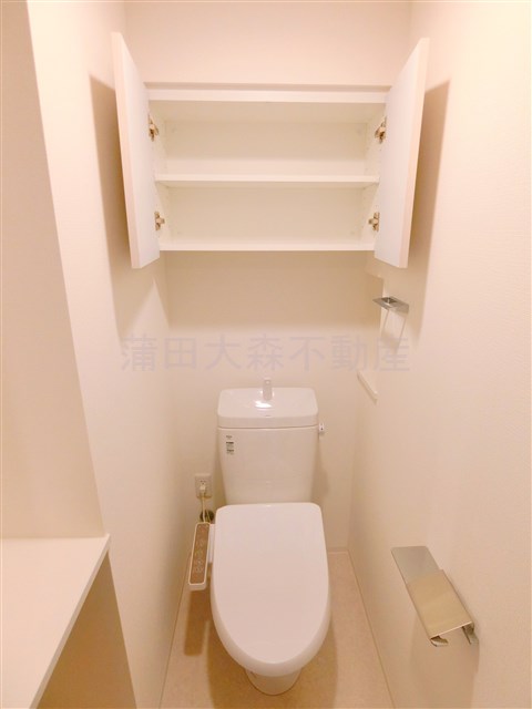 トイレ　吊戸棚と温水洗浄便座付きのトイレ