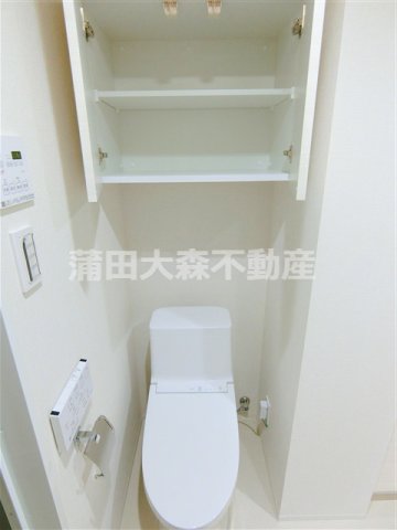 トイレ　吊戸棚と温水洗浄便座付きのトイレ