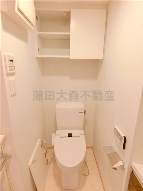 トイレ　吊戸棚と温水洗浄便座付きのトイレ
