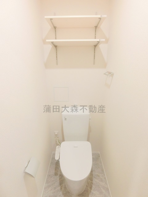 トイレ　棚と温水洗浄便座付きのトイレ