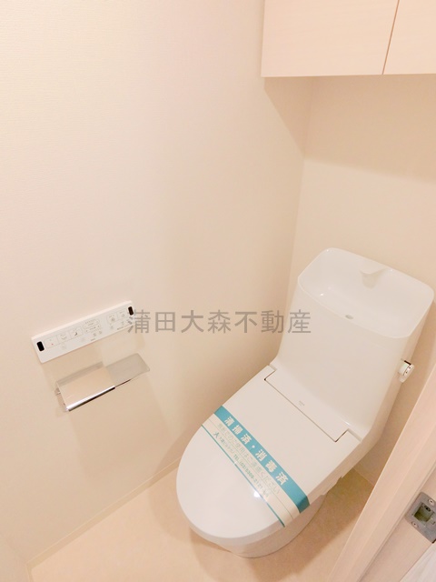 トイレ　吊戸棚と温水洗浄便座付きのトイレ