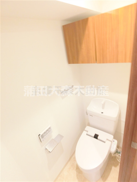 トイレ　吊戸棚と温水洗浄便座付きのトイレ