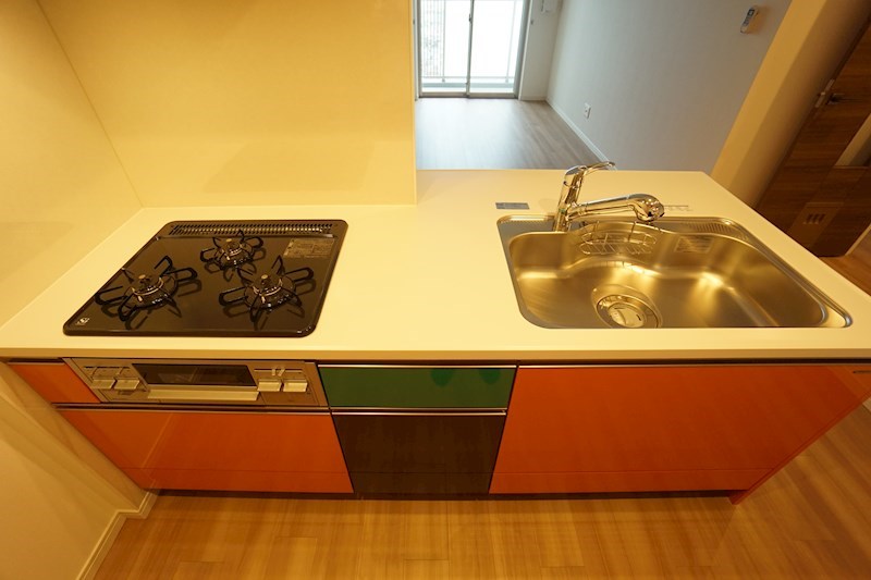 キッチン　オレンジ色の3口コンロ付のキッチン