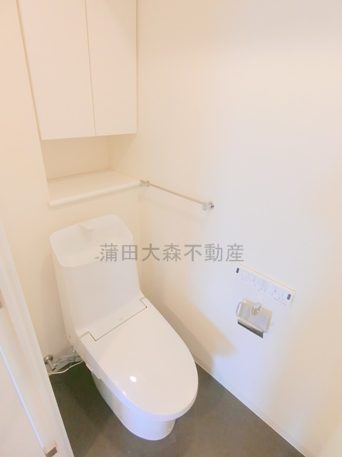 トイレ　吊戸棚と温水洗浄便座付きのトイレ