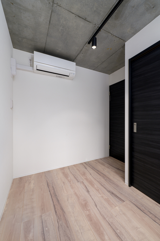 その他部屋・スペース　木目調の床にブラック建具とコンクリート天井を組み合わせた、ス