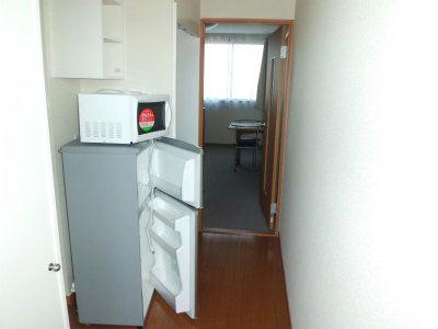 玄関　左側の扉が下駄箱。冷蔵庫とレンジの奥に台所流し台。